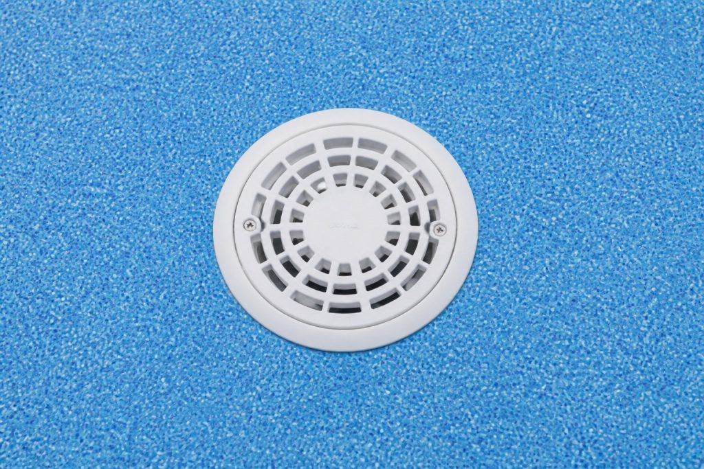 Bonde de fond blanche visible sur un liner bleu de piscine